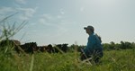 Kinzie kneeling with cattle in background